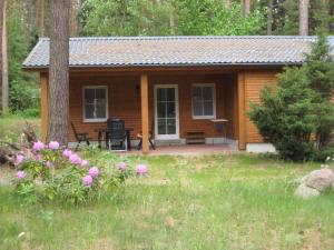 a cabin in the woods with a porch and flowers at Dependance Ferienhäuser am Kastavensee in Lychen +66 photos