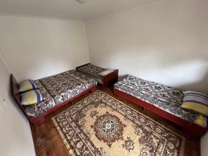 a room with three beds and a rug at Hotel Parus in Balykchy