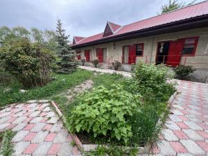 a house with a yard with plants in front of it at Hotel Parus in Balykchy +23 photos