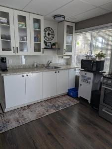 a kitchen with white cabinets and a clock on the wall at Suite in the Bush-Private Apartment in Bancroft
