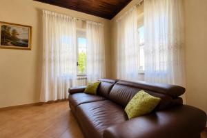 a brown leather couch in a living room with windows at Villa Natina in Pizzo +25 photos