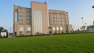 a large building with a grass field in front of it at LUXURIA INN By CHANDAN in Junagadh