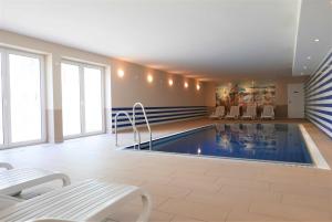 a swimming pool in a room with tables and chairs at Haus Meeresblick - Ferienwohnung Ostseeperle A 0.13 (Ref. 128670) in Baabe +16 photos