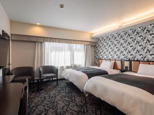 a hotel room with two beds and a desk at APA Hotel Sapporo Odori Ekimae Minami in Sapporo
