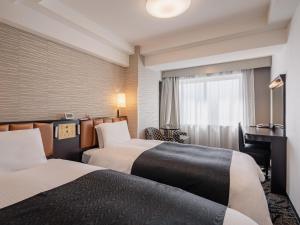 a hotel room with two beds and a desk at APA Hotel Sapporo Odori Ekimae Minami in Sapporo