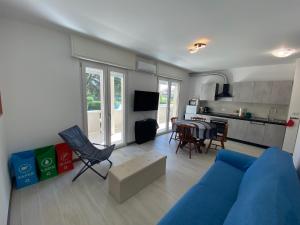 a living room with a blue couch and a kitchen at Rifugio del Mare con piscina e palestra in Loano