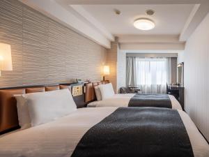 a hotel room with two beds and a window at APA Hotel Sapporo Odori Ekimae Minami in Sapporo