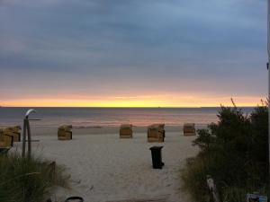 a beach with chairs and the ocean at sunset at Strandhaus Buchtmitte in Haffkrug