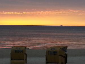 two yellow containers sitting on the beach at sunset at Strandhaus Buchtmitte in Haffkrug