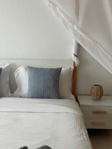 a white bed with a black and white striped pillow at Perle Bleue de Gammarth in Gammarth