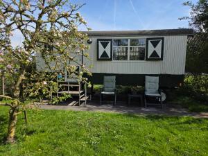 a tiny house with two chairs and a window at Pipowagen ''Slapen by Co'' in Leerdam