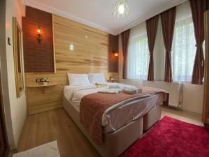 a bedroom with a large bed with a red rug at ABANT DORT MEVSİM KONAĞI HOSTEL in Dereceören