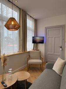 a living room with a couch and a chair and a tv at Villa Manninga in Krummhörn
