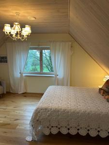 ein Schlafzimmer mit einem weißen Bett und einem Fenster in der Unterkunft Muhu Kulla Saadu puhkemaja mere ääres in Raugi