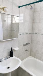 a white bathroom with a sink and a shower at JACARANDA - Alojamiento vacacional in Godoy Cruz