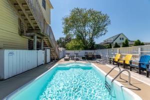 a swimming pool on a patio with chairs and a house at Shore is Fun - Duck, Poteskeet, Beach 480 Yds, 3 Min. Walk to Downtown, Pool, Hot Tub, YR Flex in Duck