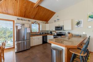 a kitchen with white cabinets and a stainless steel refrigerator at Shore is Fun - Duck, Poteskeet, Beach 480 Yds, 3 Min. Walk to Downtown, Pool, Hot Tub, YR Flex in Duck +42 photos