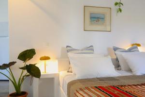 a bedroom with a bed with white pillows and a plant at Rouga - bright terrace studio in Aroniadika