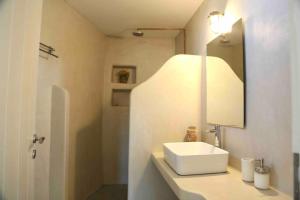 a bathroom with a white sink and a mirror at Rouga - bright terrace studio in Aroniadika