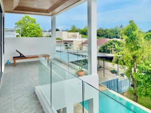 an open balcony with glass railings and a swimming pool at Anara Pool Villa 3 Bedrooms in Nathon Bay