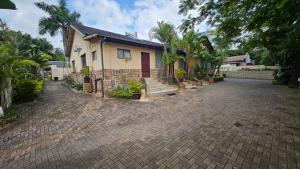a house with a brick driveway in front of it at Beginners Cove Lodge in Nelspruit