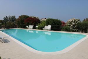 a large blue swimming pool with chairs and trees at Eden apartments 2 in Bardolino