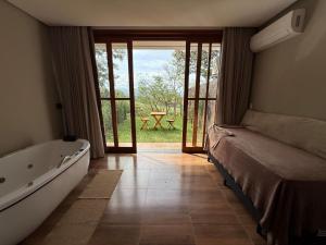 a bedroom with a tub and a bed and a window at Pousada Carraro in Delfinópolis