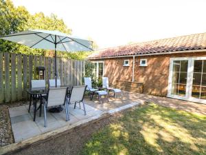 a patio with a table and chairs and an umbrella at Mill Lodge in Brisley
