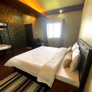 a bedroom with a bed with white sheets and a window at Stone Rose Vista in Kanatal