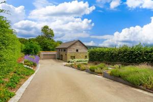a road leading to a stone building with flowers at Villa Winbomont in Malmedy