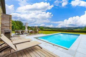 a swimming pool with a deck and chairs and a patio at Villa Winbomont in Malmedy