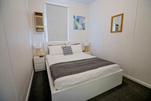 a small white bedroom with a bed and a window at Breakaway Moonta Bay in Port Moonta