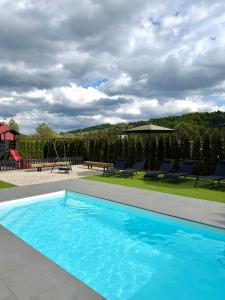 a blue swimming pool with chairs and a playground at Willa Black Wood in Istebna