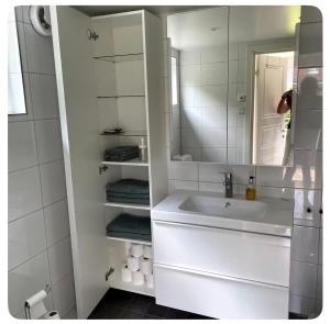 a white bathroom with a sink and a mirror at Seabreeze Pine Retreat in Åhus