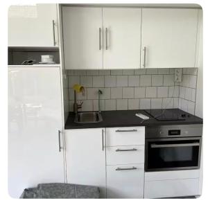 a kitchen with white cabinets and a sink and a stove at Seabreeze Pine Retreat in Åhus