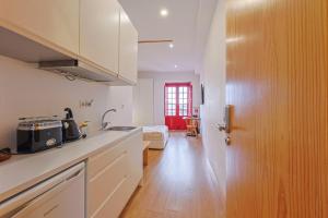 a kitchen with white cabinets and a door to a room at Casa da Sé by PURUS in Coimbra