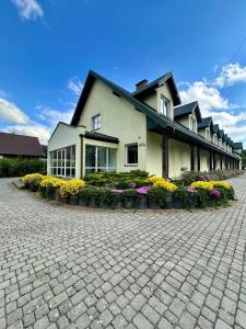 a large building with flowers in front of it at Leśna Ostoja in Górniki +8 photos