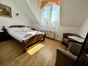 a bedroom with a bed and a chair and a window at Leśna Ostoja in Górniki