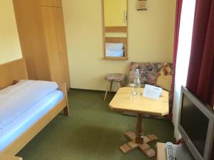 a room with a bed and a table with a tv at Hotel Sonnleiten in Reit im Winkl