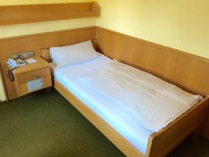 a small bedroom with a bed and a night stand at Hotel Sonnleiten in Reit im Winkl