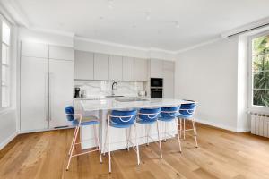 a kitchen with white cabinets and blue bar stools at Villa Leon - Centre Cannes - 4 chambres - Clim in Cannes