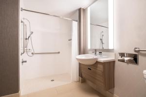 a white bathroom with a sink and a shower at SpringHill Suites West Mifflin in West Mifflin