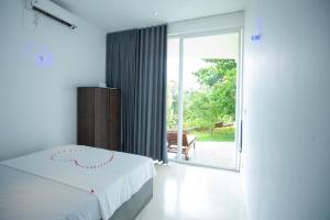 a bedroom with a bed and a sliding glass door at Sudu Appu Villa Beruwala in Beruwala