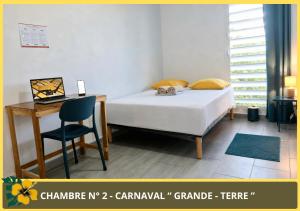 a bedroom with a bed and a desk and a table and chair at Chambre Carnaval Abymes Guadeloupe in Les Abymes