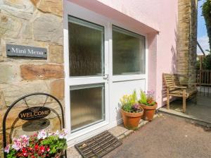 a welcome sign in front of a door with flowers at Mini Mena in St Austell