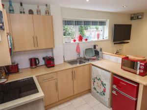 a kitchen with wooden cabinets and a red refrigerator at Mini Mena in St Austell