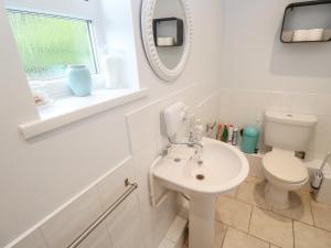 a white bathroom with a toilet and a sink at Mini Mena in St Austell