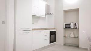a white kitchen with white cabinets and a microwave at Maison La Chicca in Molfetta