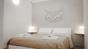 a white bedroom with a bed with towels on it at Maison La Chicca in Molfetta