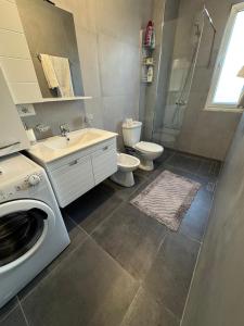 a bathroom with a washing machine and a toilet at Agnesa Apartament in Gramsh +18 photos